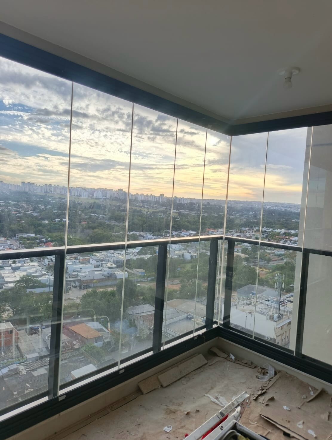 Cortina de vidro instalada em varanda com vista para o horizonte ao fim do dia