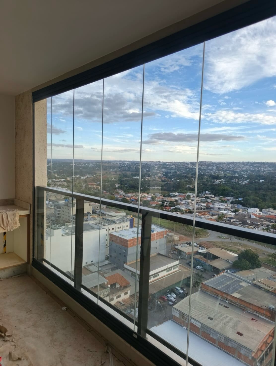 Varanda em canto com cortina de vidro e vista ampla da cidade