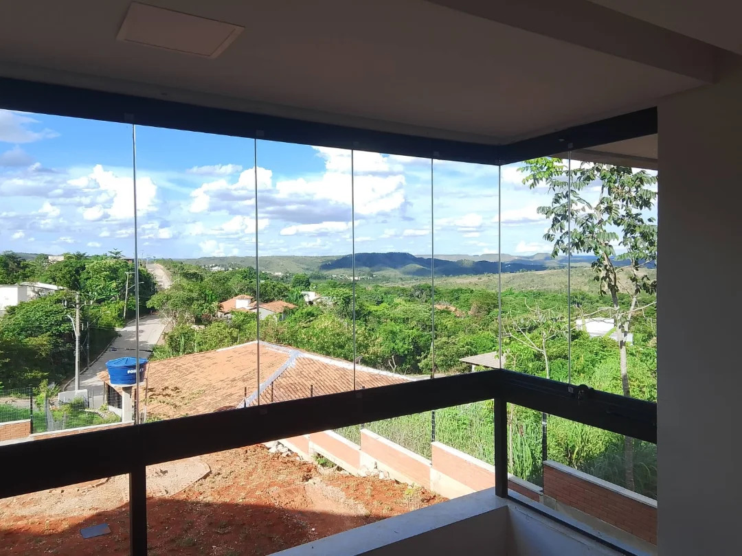 Varanda envidraçada com teto de madeira e vista aberta para a mata e o horizonte