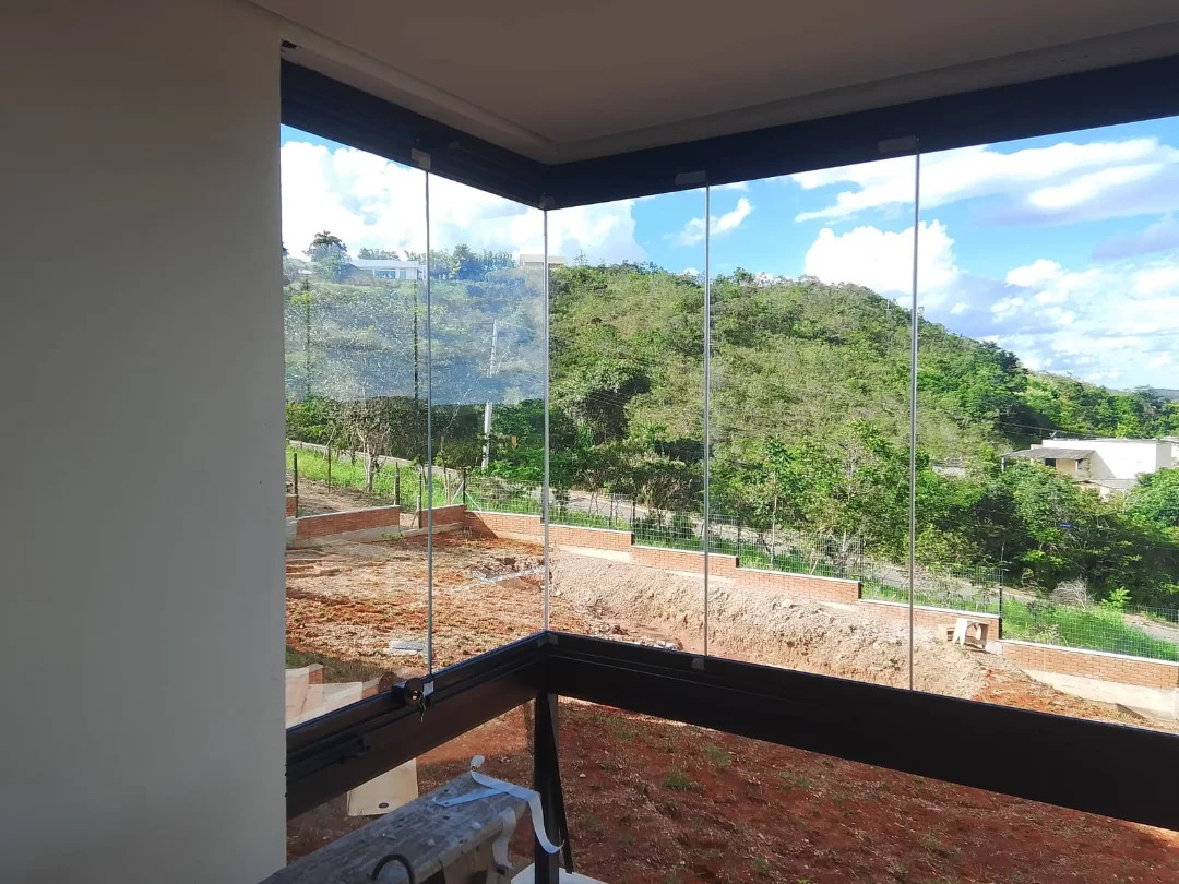 Varanda com cortina de vidro e vista para área de mata
